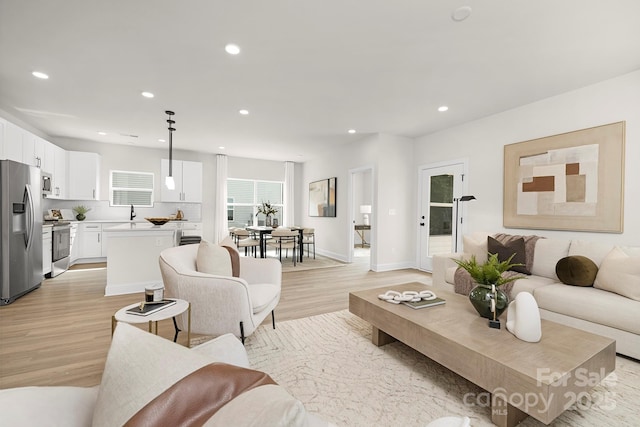 living room with recessed lighting, baseboards, and light wood-style floors