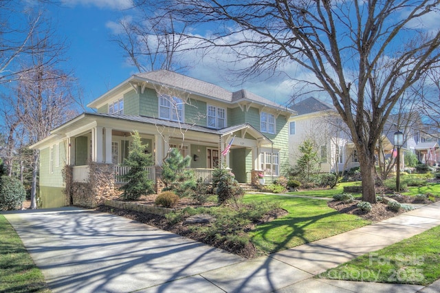 view of front of house with a front yard, covered porch, metal roof, and a standing seam roof