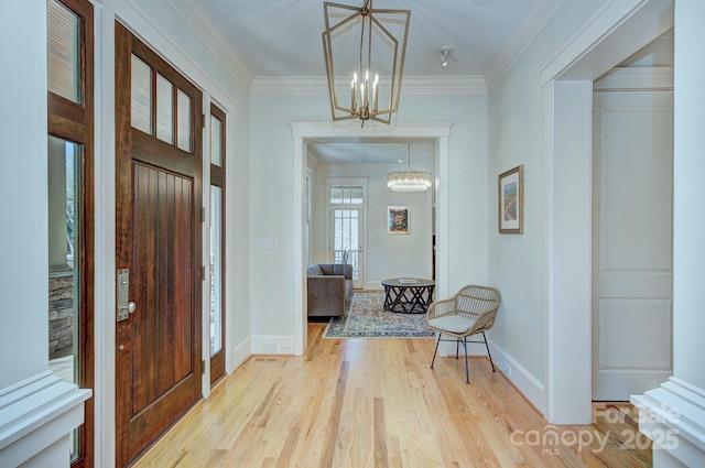 entryway with baseboards, ornamental molding, a notable chandelier, and wood finished floors