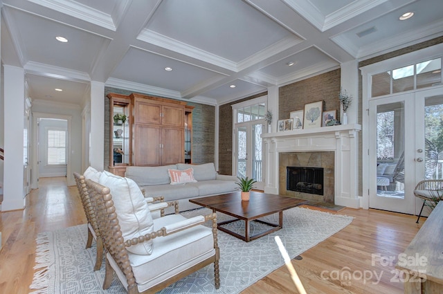 living area featuring coffered ceiling, a tiled fireplace, beamed ceiling, french doors, and light wood-style floors