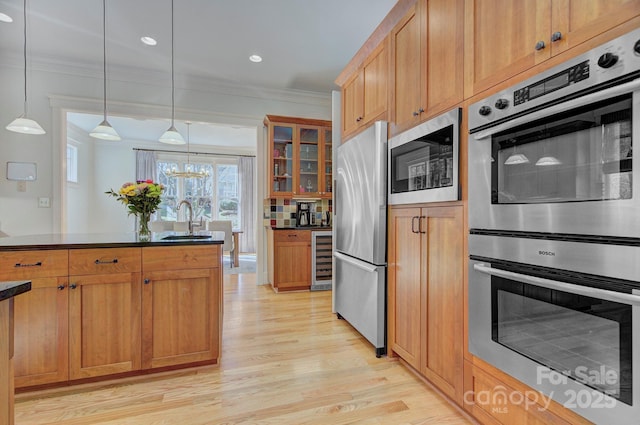 kitchen featuring dark countertops, appliances with stainless steel finishes, a sink, and ornamental molding