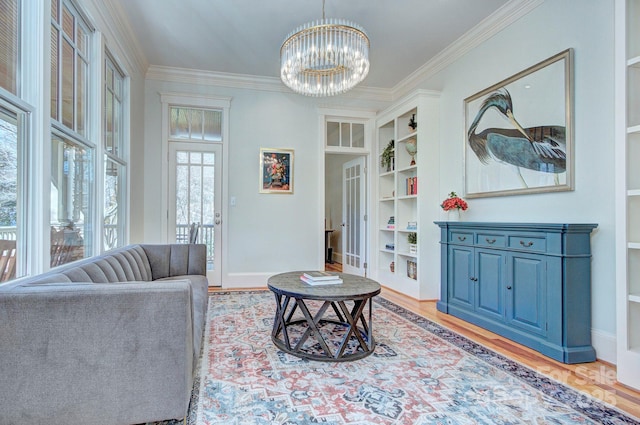 living area with built in features, crown molding, light wood-style flooring, an inviting chandelier, and baseboards