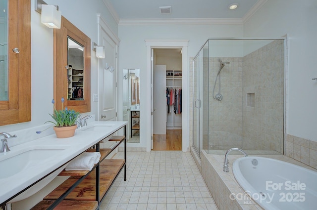 bathroom with a stall shower, ornamental molding, a garden tub, and a sink