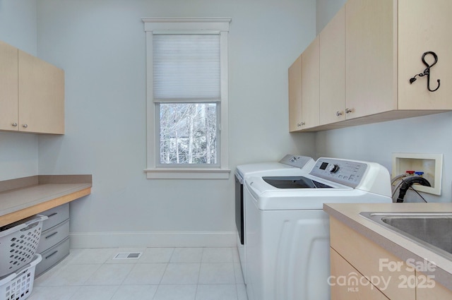 laundry room featuring light tile patterned flooring, separate washer and dryer, visible vents, baseboards, and cabinet space