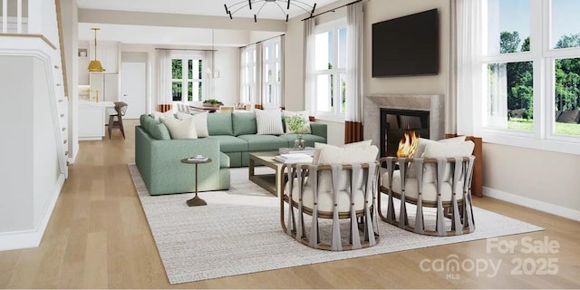 living room with a premium fireplace, light wood-style flooring, and baseboards