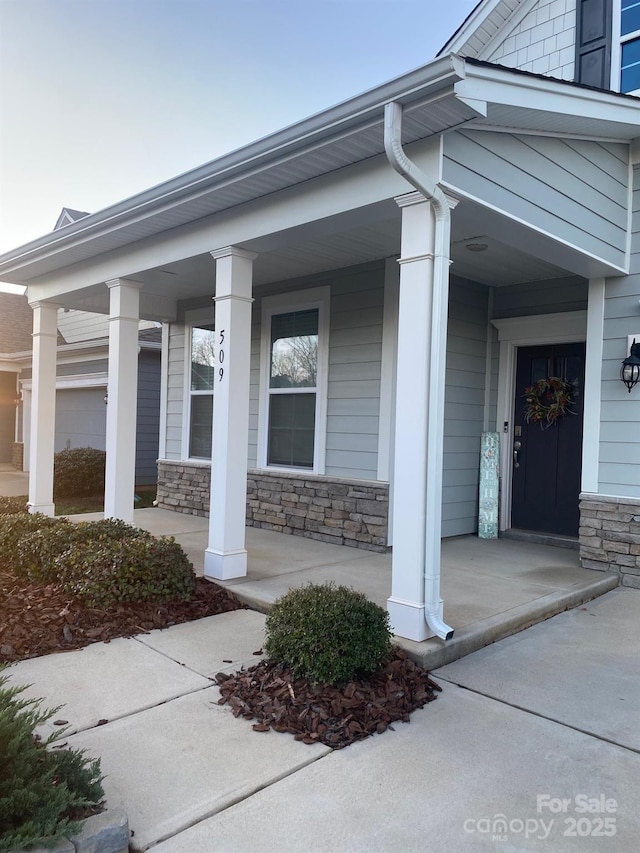 entrance to property featuring stone siding and covered porch