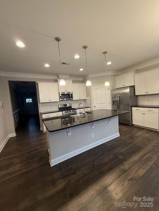 kitchen featuring visible vents, appliances with stainless steel finishes, dark countertops, dark wood finished floors, and crown molding