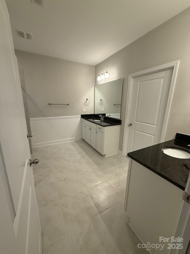 full bathroom featuring wainscoting, two vanities, a sink, and visible vents