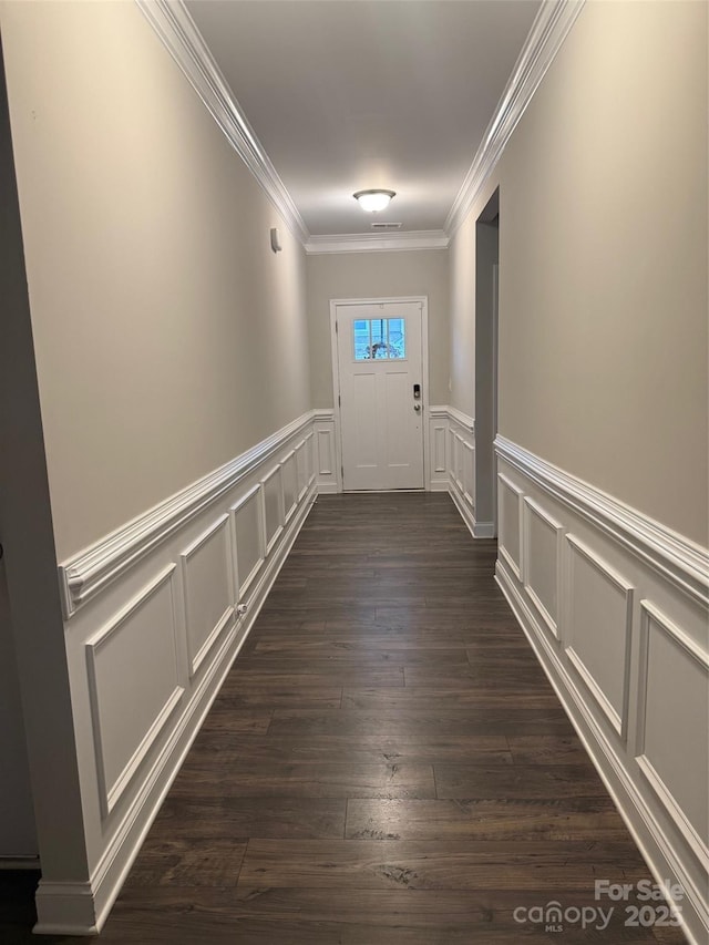 corridor featuring dark wood-style floors, ornamental molding, and a decorative wall