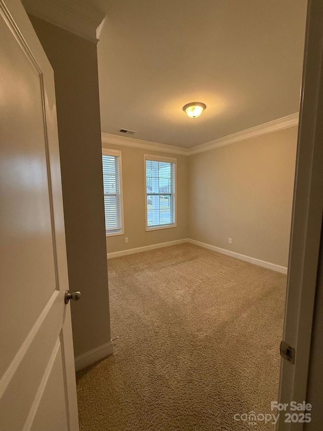 unfurnished room with baseboards, carpet floors, visible vents, and crown molding