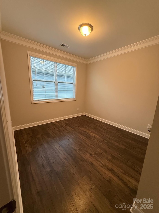 spare room featuring dark wood-style floors, visible vents, and crown molding