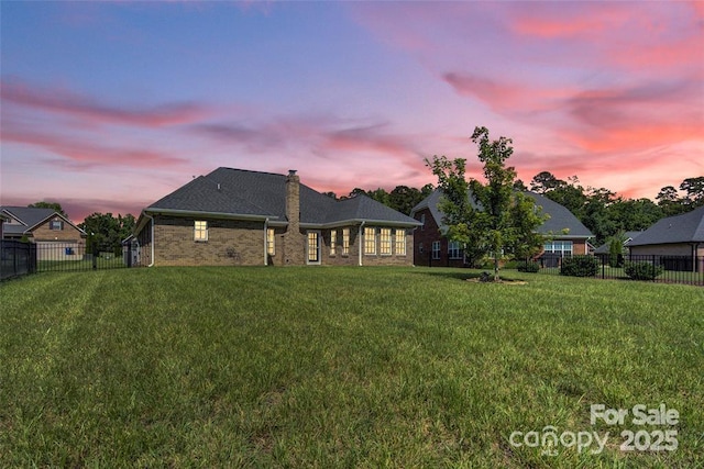 back of house with fence, a lawn, and brick siding