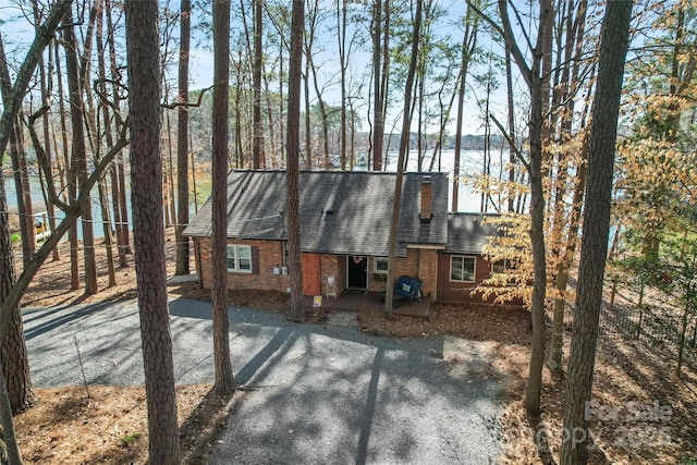 exterior space featuring roof with shingles, brick siding, a chimney, and fence