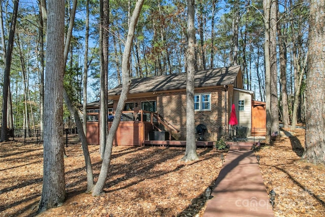 view of front facade featuring fence, a deck, and brick siding