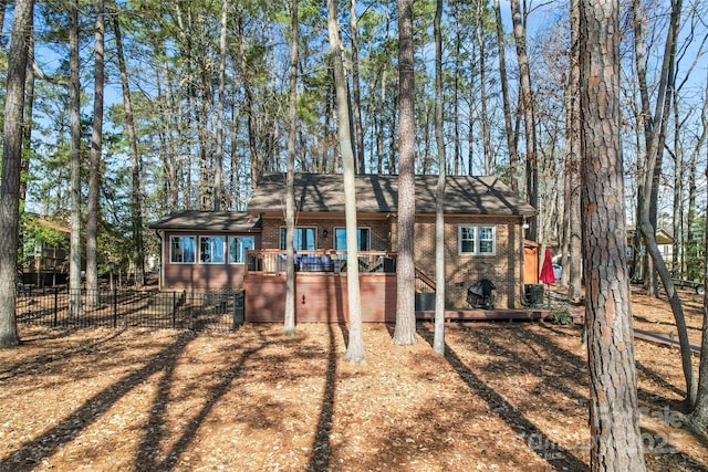 exterior space featuring brick siding, fence, a deck, and central AC unit