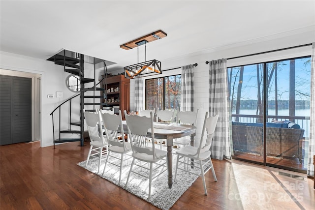 dining area with crown molding, a water view, visible vents, wood finished floors, and stairs