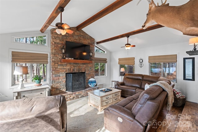 living area featuring a wealth of natural light, vaulted ceiling with beams, a stone fireplace, and wood finished floors