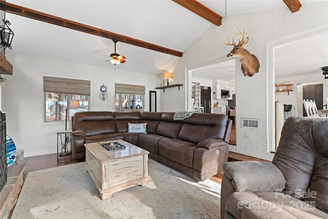 living area with lofted ceiling with beams, brick wall, wood finished floors, visible vents, and a ceiling fan