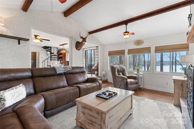 living area featuring lofted ceiling with beams, stairs, light wood-style flooring, and a ceiling fan