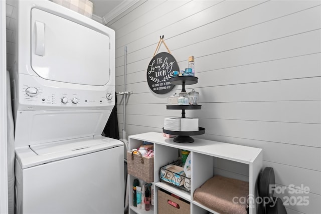 washroom featuring laundry area, stacked washer / dryer, and crown molding