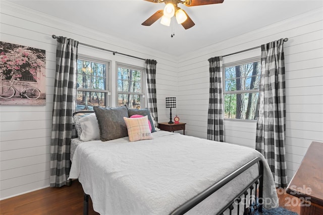 bedroom with multiple windows, wood walls, and wood finished floors