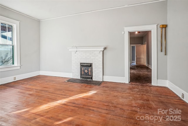 unfurnished living room with crown molding, wood finished floors, and baseboards