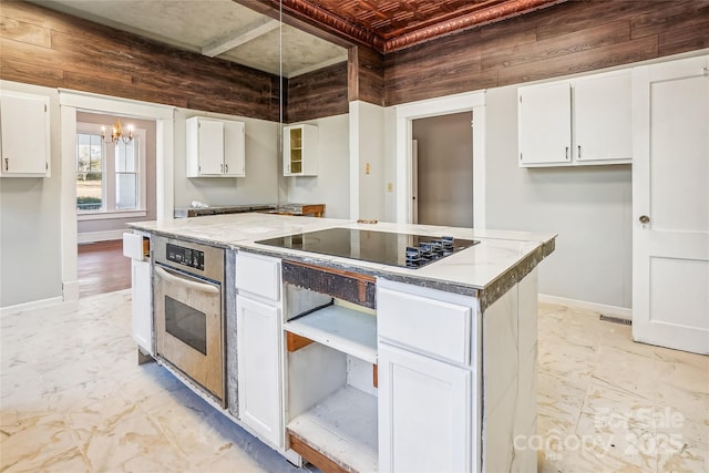 kitchen with stainless steel oven, baseboards, white cabinetry, and black electric cooktop