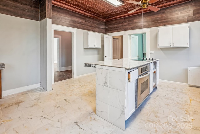 kitchen with an ornate ceiling, oven, white cabinets, and baseboards