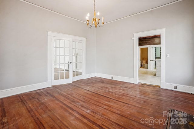 unfurnished room with baseboards, wood finished floors, and a notable chandelier