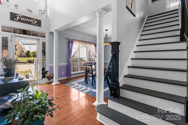 foyer featuring wood finished floors, baseboards, stairway, ornate columns, and crown molding