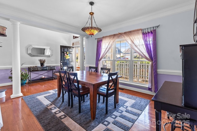 dining area with wood finished floors and decorative columns