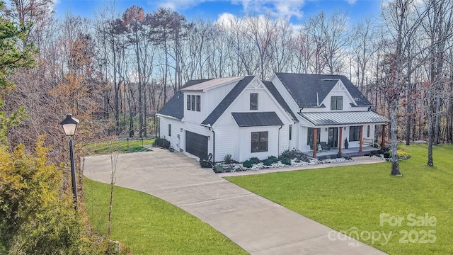 modern farmhouse with metal roof, covered porch, driveway, a standing seam roof, and a front yard