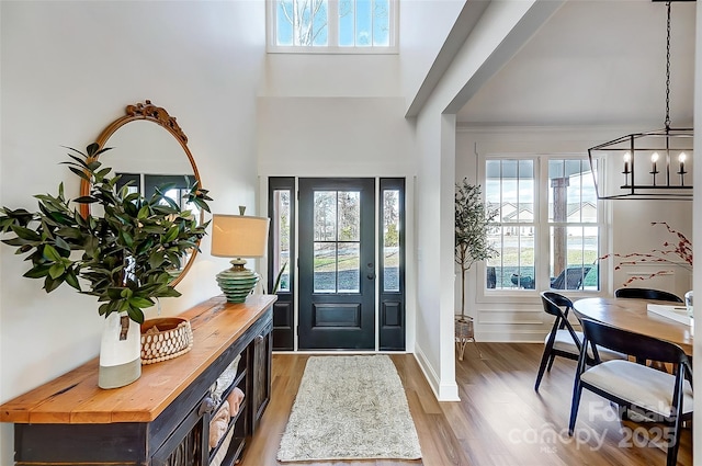 foyer entrance featuring a chandelier, wood finished floors, and a towering ceiling