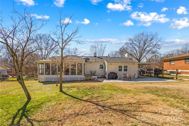 rear view of property featuring a sunroom, a patio, fence, and a lawn