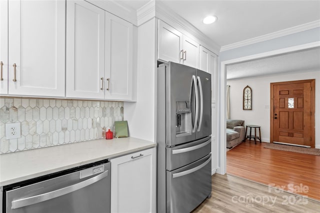 kitchen featuring crown molding, stainless steel appliances, backsplash, light wood-style floors, and white cabinetry