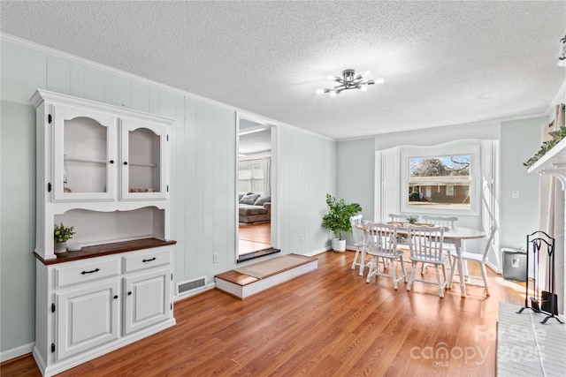 dining room featuring light wood-type flooring, visible vents, a chandelier, and ornamental molding