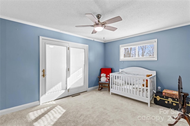 bedroom with a textured ceiling, light carpet, visible vents, baseboards, and a nursery area