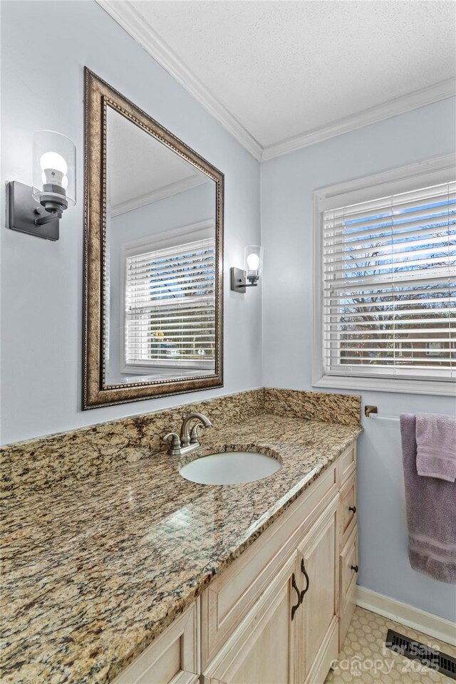 bathroom featuring baseboards, visible vents, vanity, and crown molding