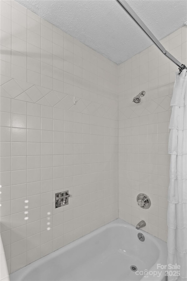 full bath with shower / bath combo and a textured ceiling