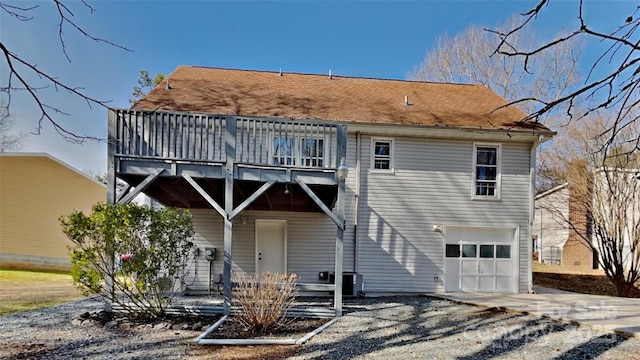 rear view of property with driveway, a garage, and central AC