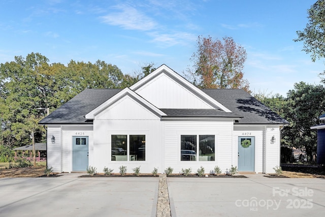 modern inspired farmhouse featuring roof with shingles