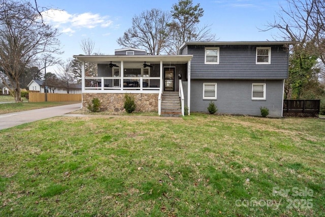 split level home featuring ceiling fan, stairs, fence, and a front yard