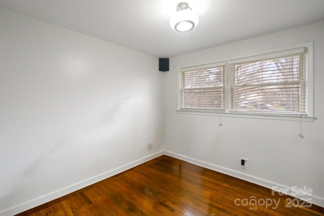 spare room featuring baseboards and wood finished floors