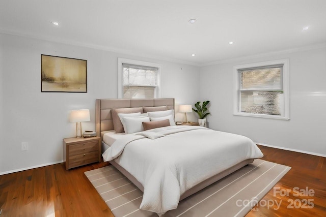 bedroom with ornamental molding, wood finished floors, and baseboards