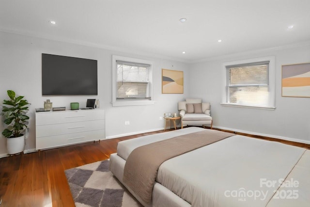 bedroom with ornamental molding, multiple windows, baseboards, and wood finished floors