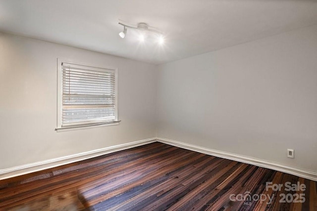 empty room featuring dark wood-style floors and baseboards