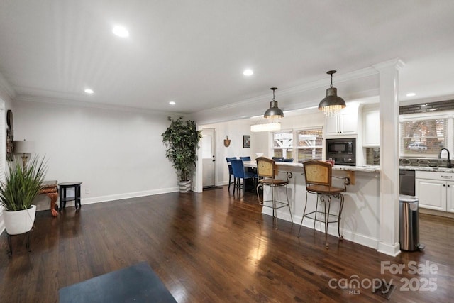 kitchen featuring black microwave, a breakfast bar, white cabinetry, dark wood finished floors, and pendant lighting