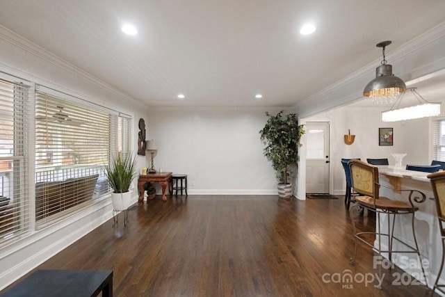 interior space featuring recessed lighting, wood finished floors, baseboards, a kitchen bar, and crown molding