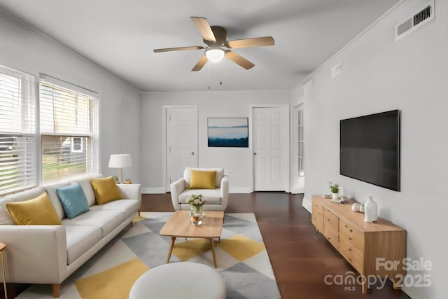 living room featuring baseboards, visible vents, a ceiling fan, ornamental molding, and wood finished floors