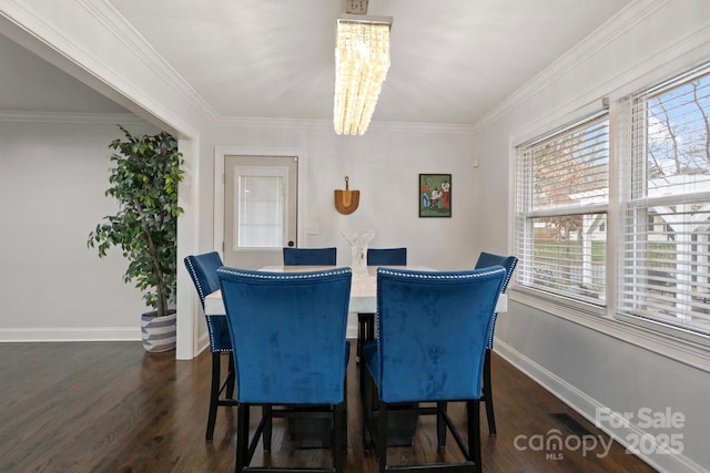 dining space with dark wood-type flooring, crown molding, a notable chandelier, and baseboards